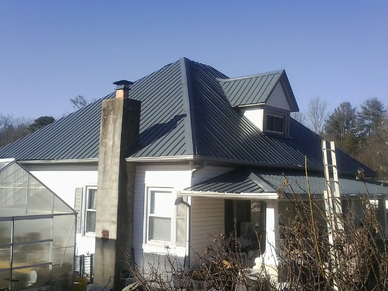 Dark blue standing seam metal roof on a white farmhouse with dormer — Slate & Tile Roof Repair by Roofing Brothers in Hanscom Afb