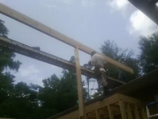 Carpenter setting a ridge beam over a new addition frame — Ice Dam Removal by Roofing Brothers in Hanscom Afb