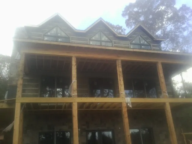 Dormers and porch framing on a large log home under construction — Roof Coating work by our crew in Hanscom Afb