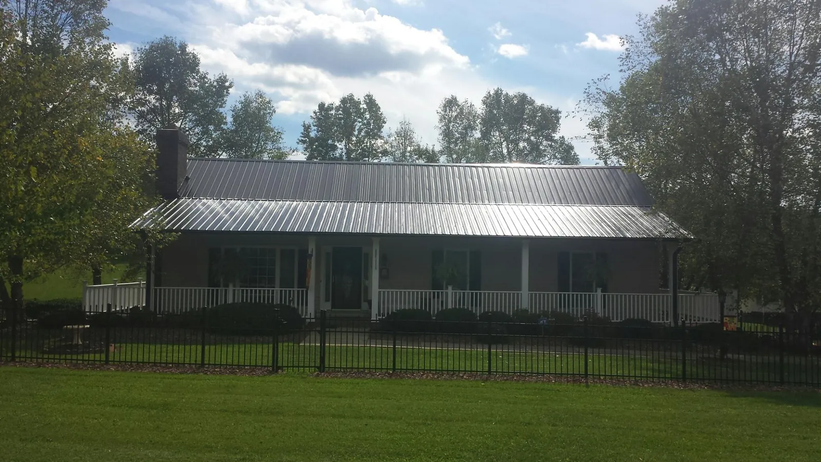 Gray metal roof on a brick ranch with a full width front porch — Gutter Guard Installation work by our crew in Hanscom Afb