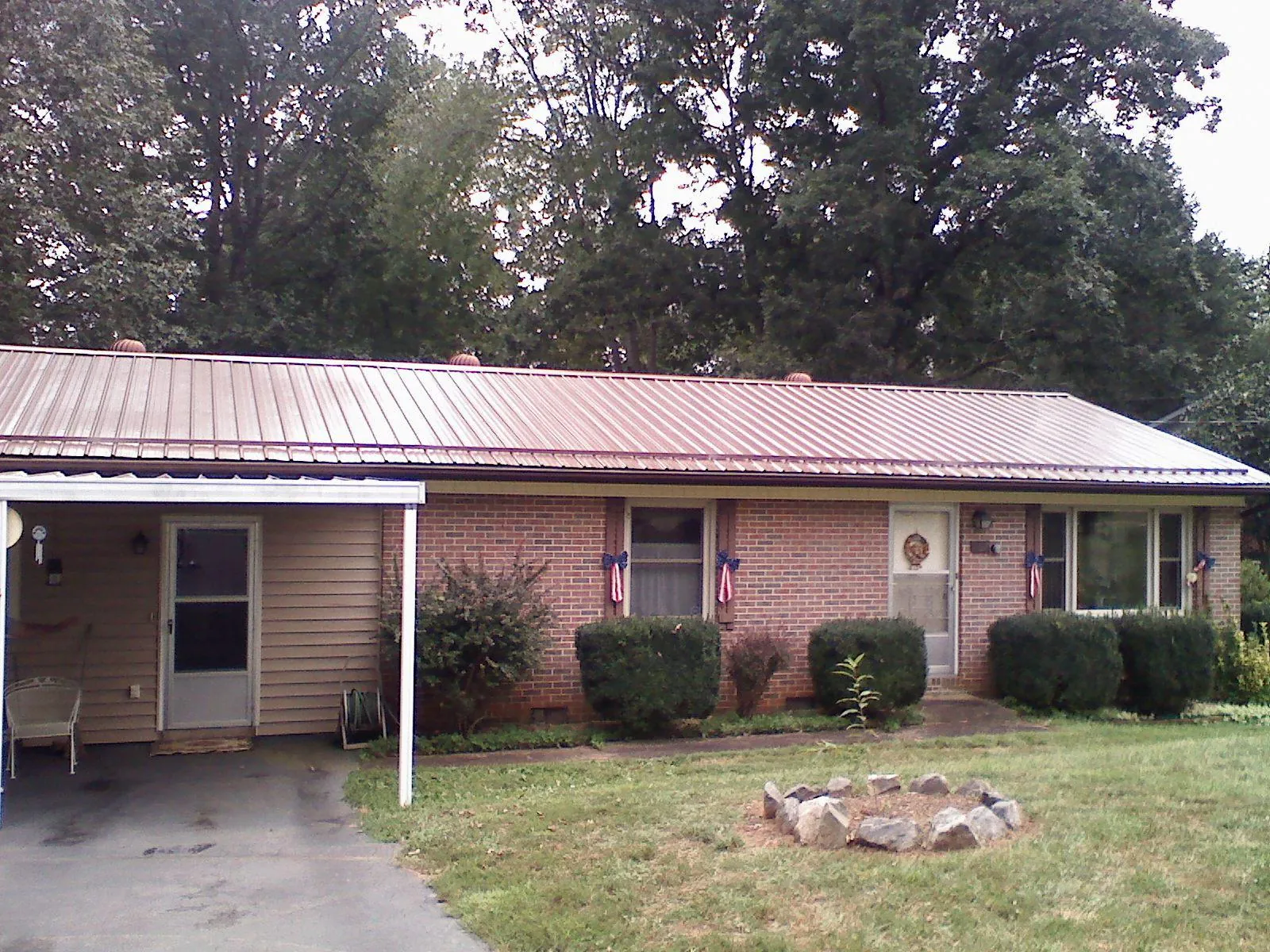 Bronze metal roof and carport on a brick ranch home — Roof Repair work by our crew in Hanscom Afb