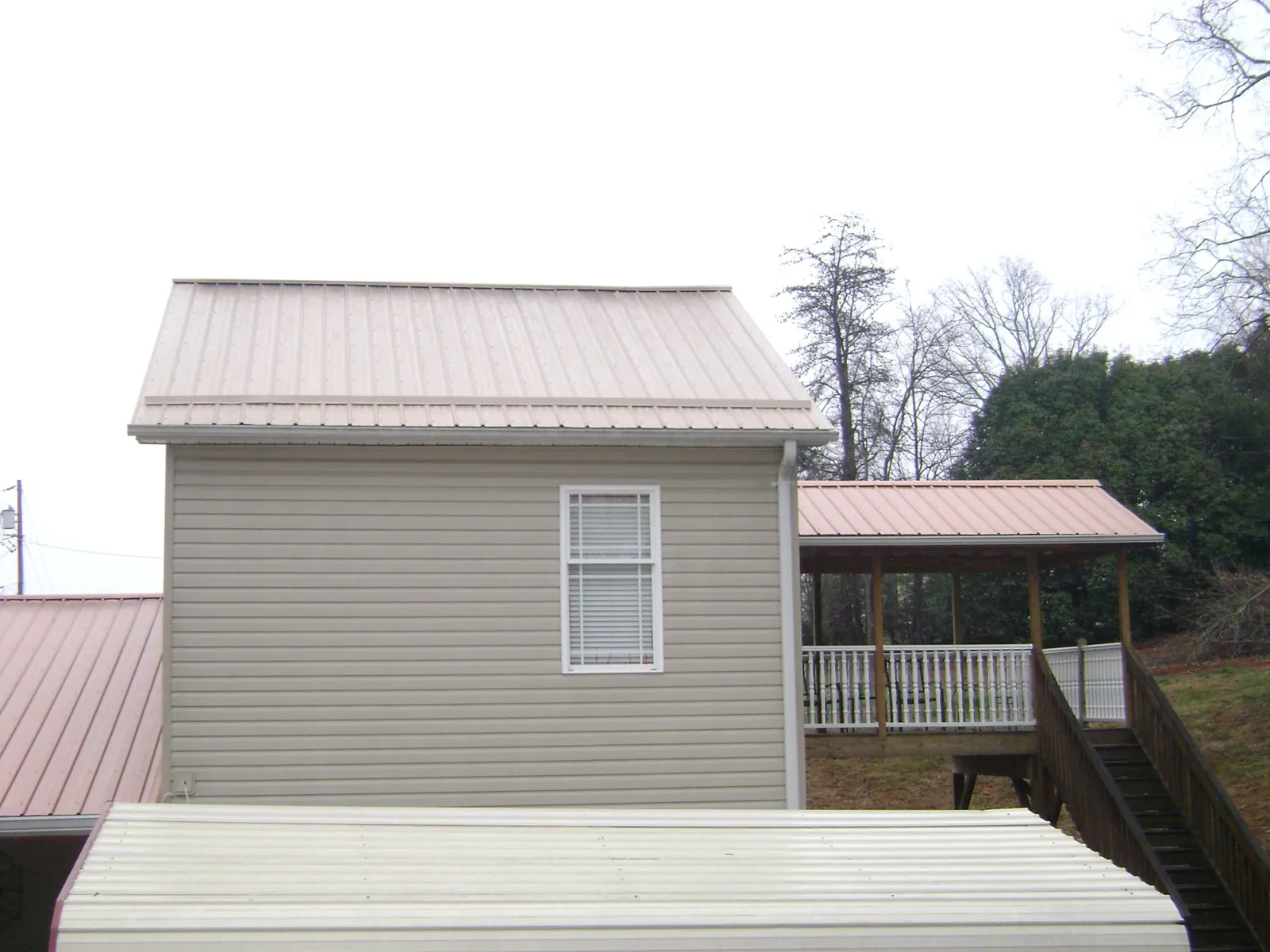 Tan metal roofs on a two story addition and attached porch, from a Roof Replacement job in Hanscom Afb