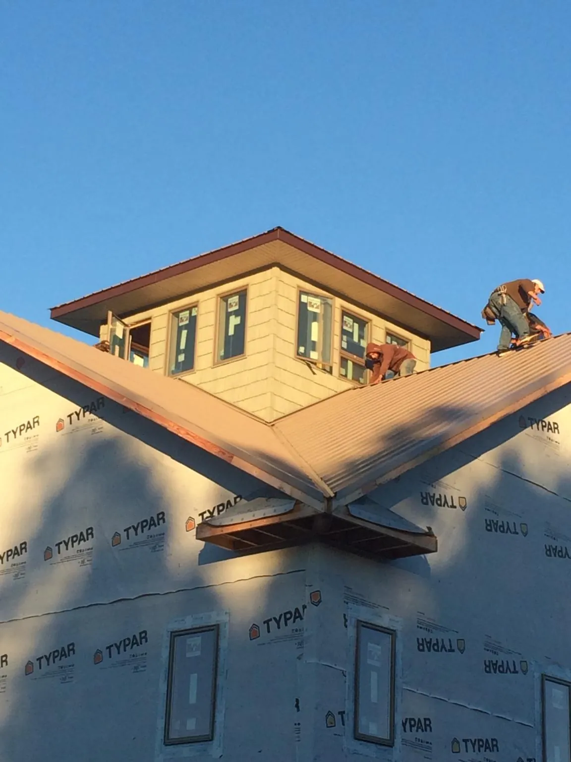 Roofers working around a rooftop cupola on a new metal roof at sunset — Roof Waterproofing in Hanscom Afb by Roofing Brothers